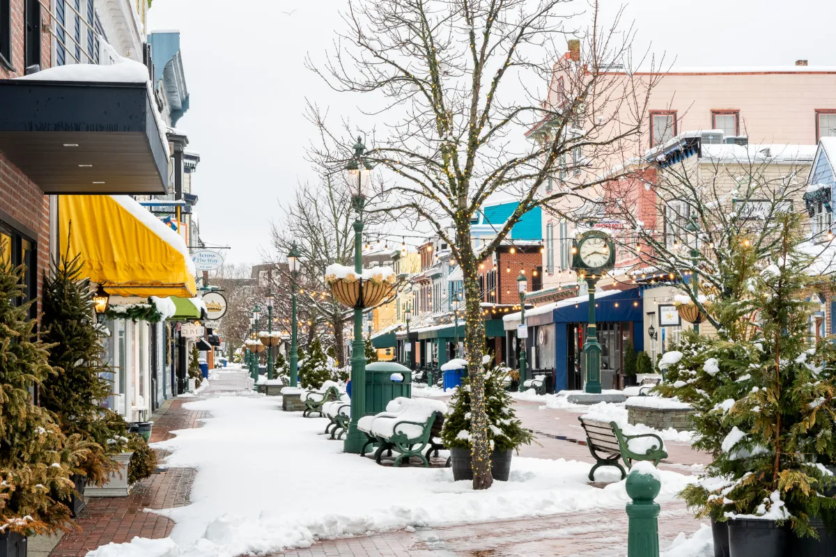 Snow-covered Washington Street Mall in Cape May, with colorful storefronts, benches, and holiday lights